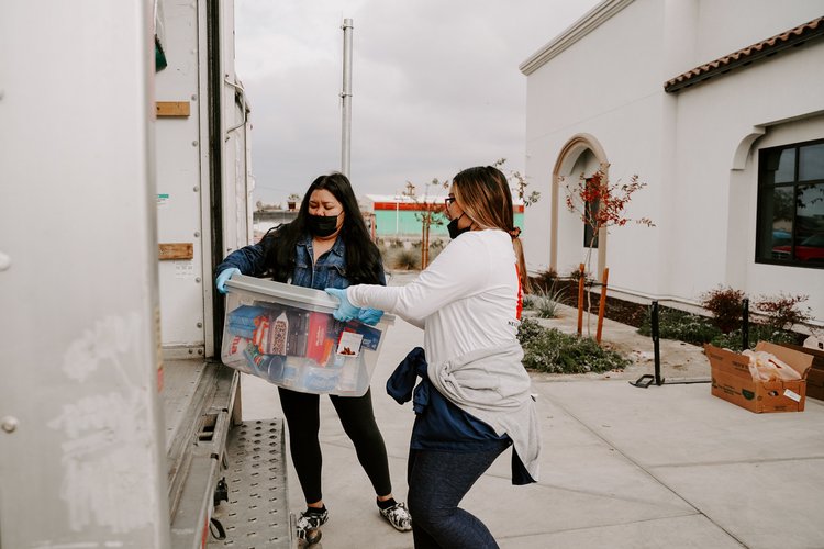 Women loading a bin onto a truck