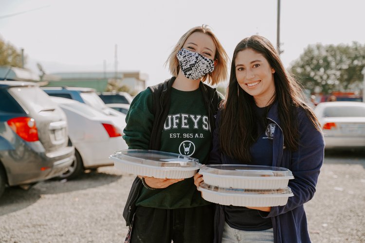 Two women holding platters at a Thanksgiving food drive