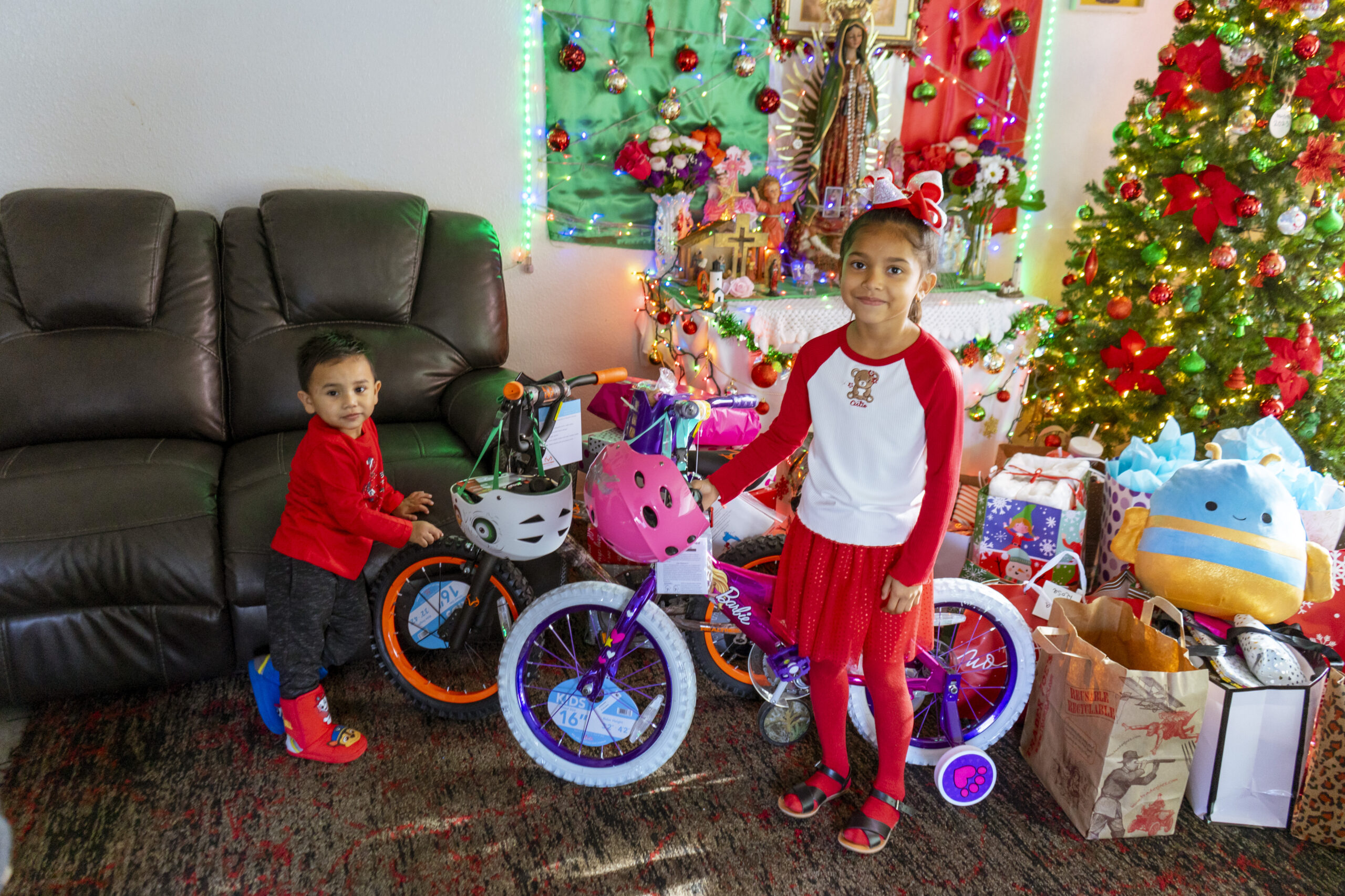 two children standing with bicycles in front of the Christmas tree