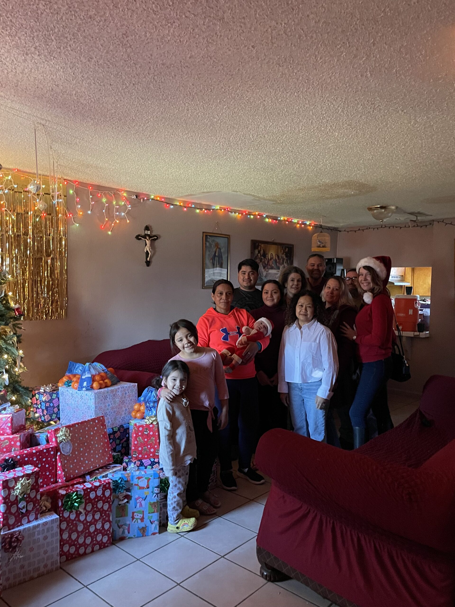a group of people standing and smiling in front of Christmas presents